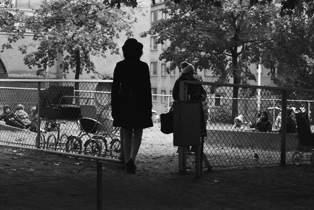 Etu-Töölön Apollonpuistikko Apollonkadun ja Minervankadun kulmasta. Portilla nainen ja puistotäti, taustalla lastenvaunuja ja lapsia hiekkalaatikolla. Taustalla vasemmalla Minervanpolku 2 ja oikealla Minervankatu 4.