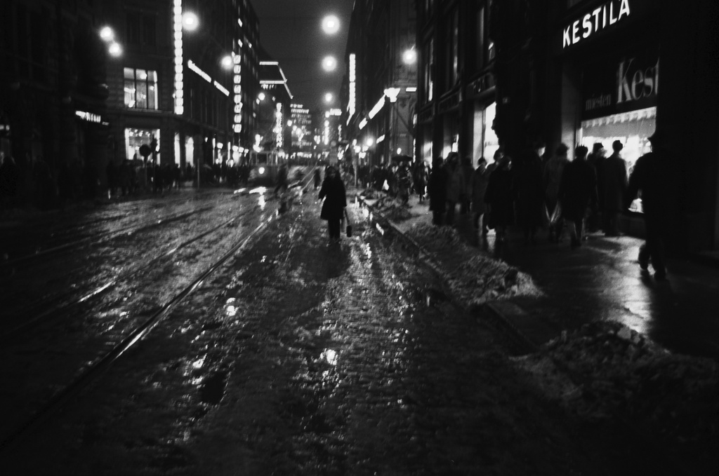 Kluuvi, Aleksanterinkatu. Jalankulkijoita ruuhka-aikaan talvipäivän pimetessä loskaisella, sumuisella Aleksanterinkadulla. Kävelykatukokeilu (12.6.1970-8.1.1971) on juuri päättynyt. Käveleekö yksi ihminen vielä vanhasta muistista ajoradalla? Näkymä Kluuvikadun suunnalta Mikonkadulle päin, oikealla Aleksanterinkatu 13, jossa Kestilän, HOK:n ja Aleksi 13:n myymälät.