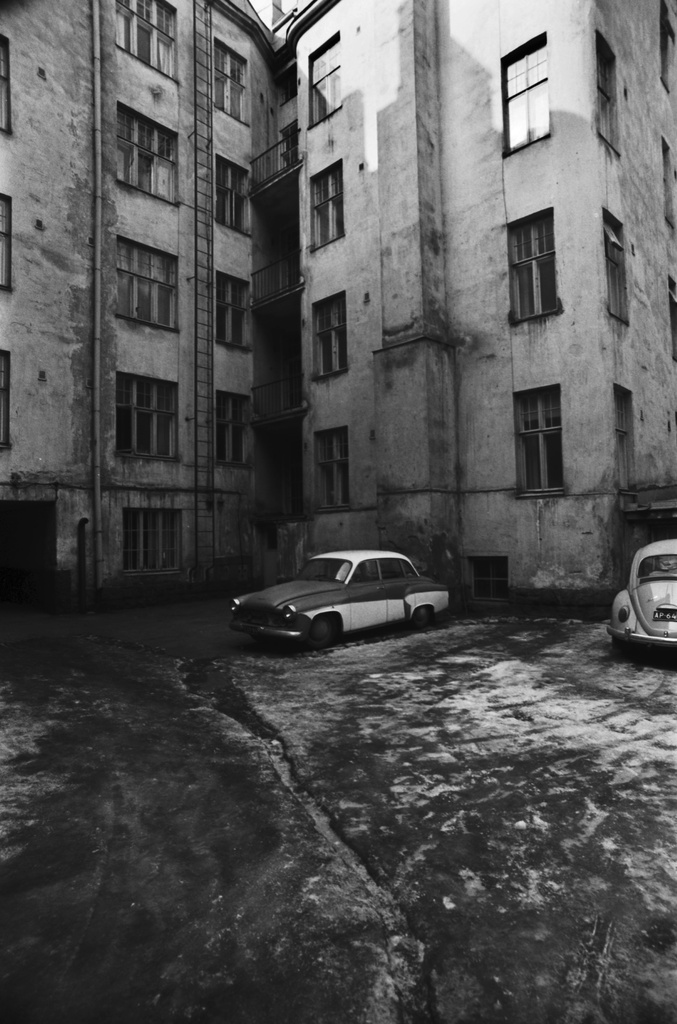 Lapinrinne 4 ? Kaksi autoa, keskellä Wartburg hieman rapistuneen kerrostalon pihalla Kampissa.