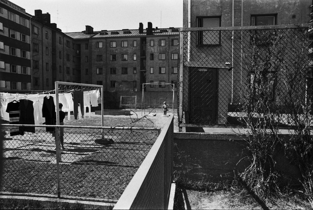 Neljäs linja 26. Pihanäkymä luoteeseen Kolmas linja - Castréninkatu - Neljäs linja - Suonionkatu -katujen ympäröimästä korttelista. Vasemmalla verkkoaidan takana Kolmas linja 25:n piha, jossa pyykkiä kuivumassa pyykkitelineessä sekä hiekkalaatikko ja keinut. Oikealla Neljäs linja 26, taustalla vasemmalla Castréninkatu 3.