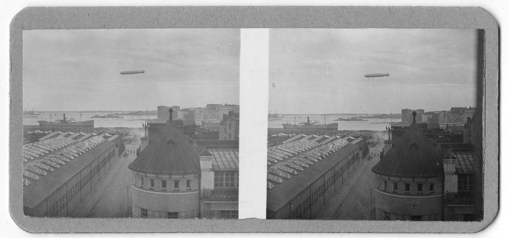 Ilmalaiva Graf Zeppelin Helsingin yllä. Vasemmalla Wärtsilän korttelin rakennuksia (sittemmin purettu). Oikealla Hämeentie 5 (Arbetets Vänner i Sörnäs, nykyään tontin osoite on Hämeentie 3). Rakennus purettu tammikuussa 1969. Stereografinen kuva.