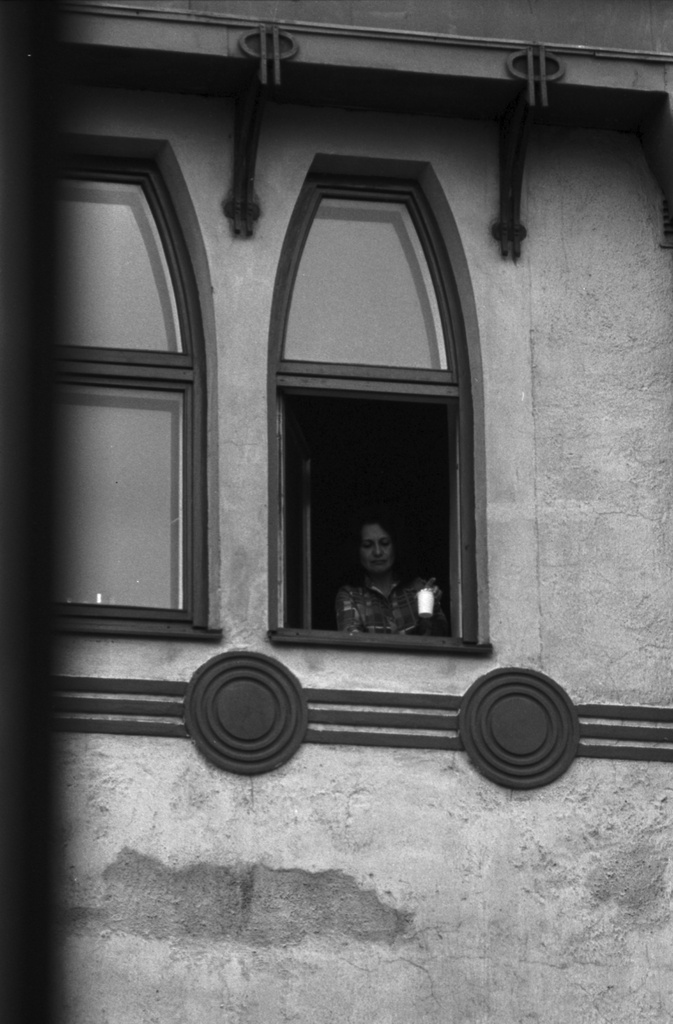Meritullinkatu 26. Nainen purkki kädessä asuntonsa avoimen ikkunan ääressä Meritullinkatu 26:n ylimmässä kerroksessa.