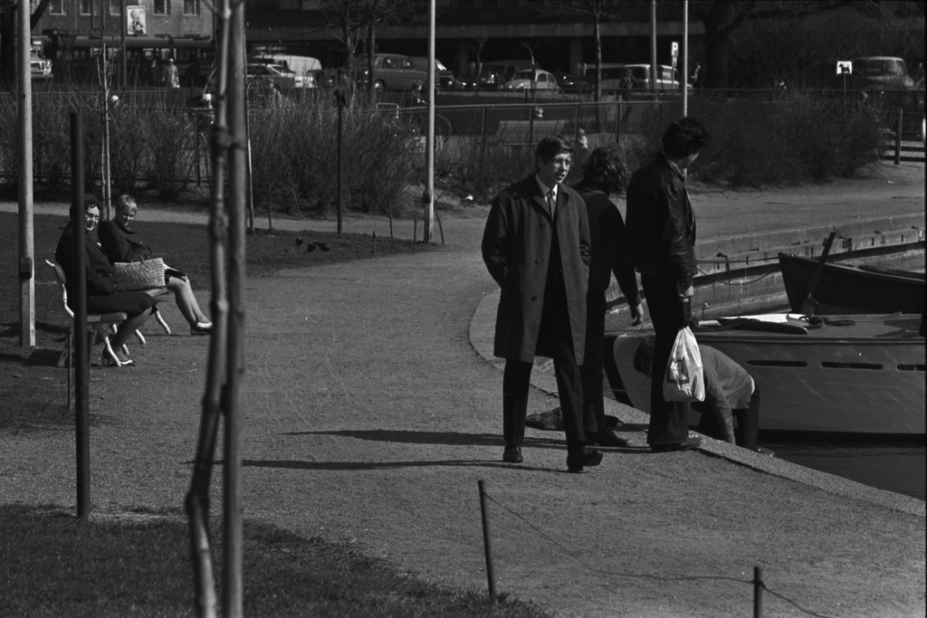 Tokoinranta. Ihmisiä, mm. nuorisoa muovikasseineen kevätauringossa Eläintarhanlahden rannan Säästöpankinrannan puoleisessa päässä.