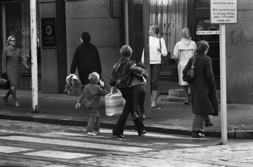 Aleksanterinkatu 44. Jalankulkijoita, mm. nainen ylittämässä suojatietä lasta kainalossaan roikottaen Aleksanterinkadun ja Mikonkadun kulmassa kävelykatukokeilun aikoihin.