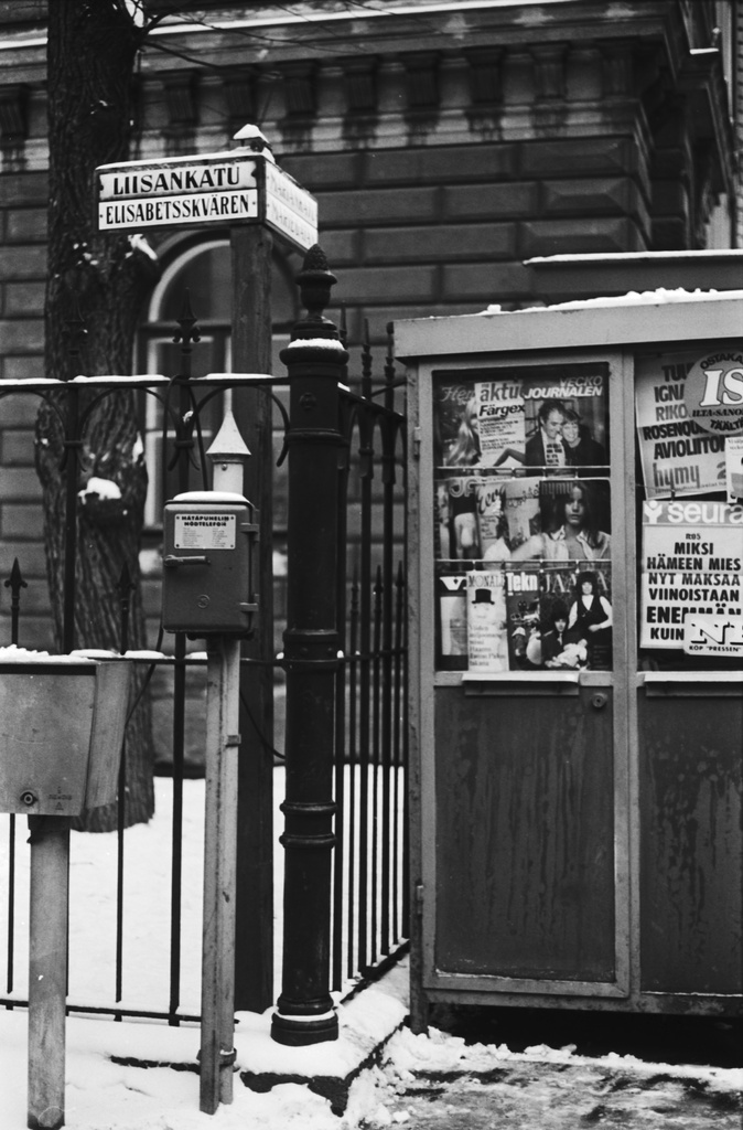Kruununhaka, Liisankatu. Näkymä Liisankadulta Mariankadun kulmasta. Vasemmalla hätäpuhelin, oikealla lehtikioskin nurkka, jonka ikkunassa aikakauslehtiä. Taustalla Mariankatu 23.