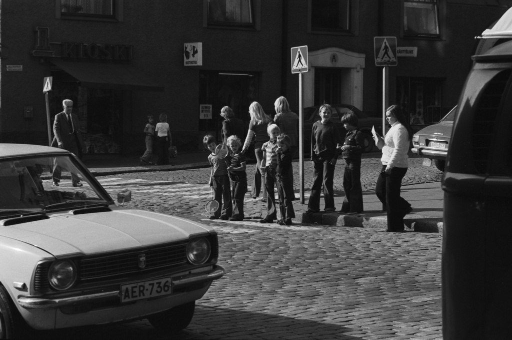 Liisankatu. Joukko eri-ikäisiä poikia, osa suojatiellä seisten, odottamassa kadunylitystä Liisankadun ja Snellmaninkadun kulmassa. Kruununhaan asukasyhdistys on tehnyt ehdotuksen liikennevalojen saamiseksi vilkkaaseen risteykseen, jota mm. kahden koulun lapset päivittäin käyttävät.