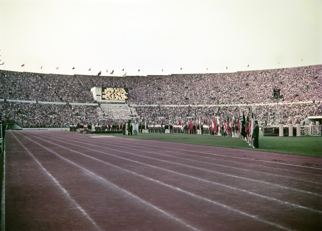 Helsingin olympialaiset 1952. Kisojen päättäjäiset Olympiastadionilla. Katsomon pohjoiskaarre ja kenttänurmella urheilijoita kansallislippujen kanssa.