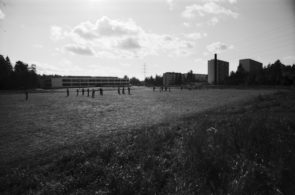 Puotinharju. Näkymä Olavinlinnanpolulta päin etelän suuntaan. Oikealla lapsia kentällä Puotinharjun yhteiskoulun edustalla, vasemmalla Kajaaninlinnantien kerrostaloja.
