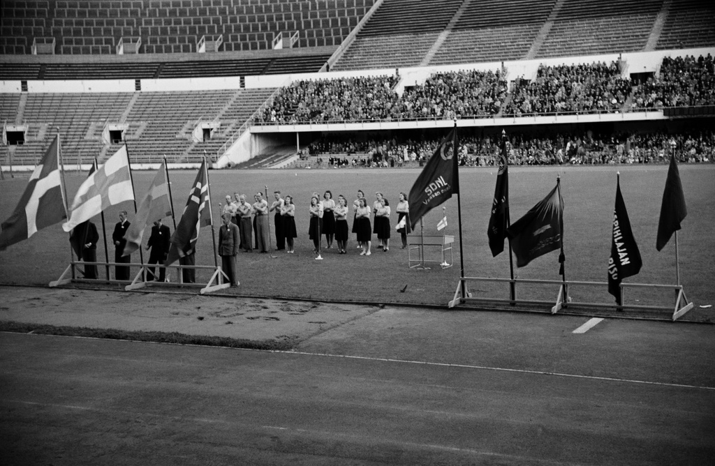 Lauluesitys työväenliikkeen juhlassa Stadionilla. Esillä mm. Suomen Demokraattisen Nuorisoliiton (SDNL) ja Pohjoismaiden lippuja.