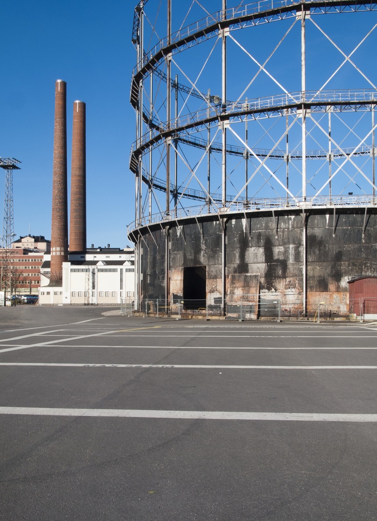 Suvilahden kaasukellon puhdistus. Kaksi, maakaasujakelun alkamisen jälkeen käytöstä tarpeettomana poistettua kaasukelloa. Vasemmalla sähkölaitos ja sen piiput. Oikealla teräsrakenteinen kello ja sen ns. haalausaukko, joka on tehty työkoneille puhdistusta varten. Aukko on myöhemmin suljettu. Suvilahden energiantuotantoalueen rakennukset on suunnitellut Selim A. Lindqvist.
