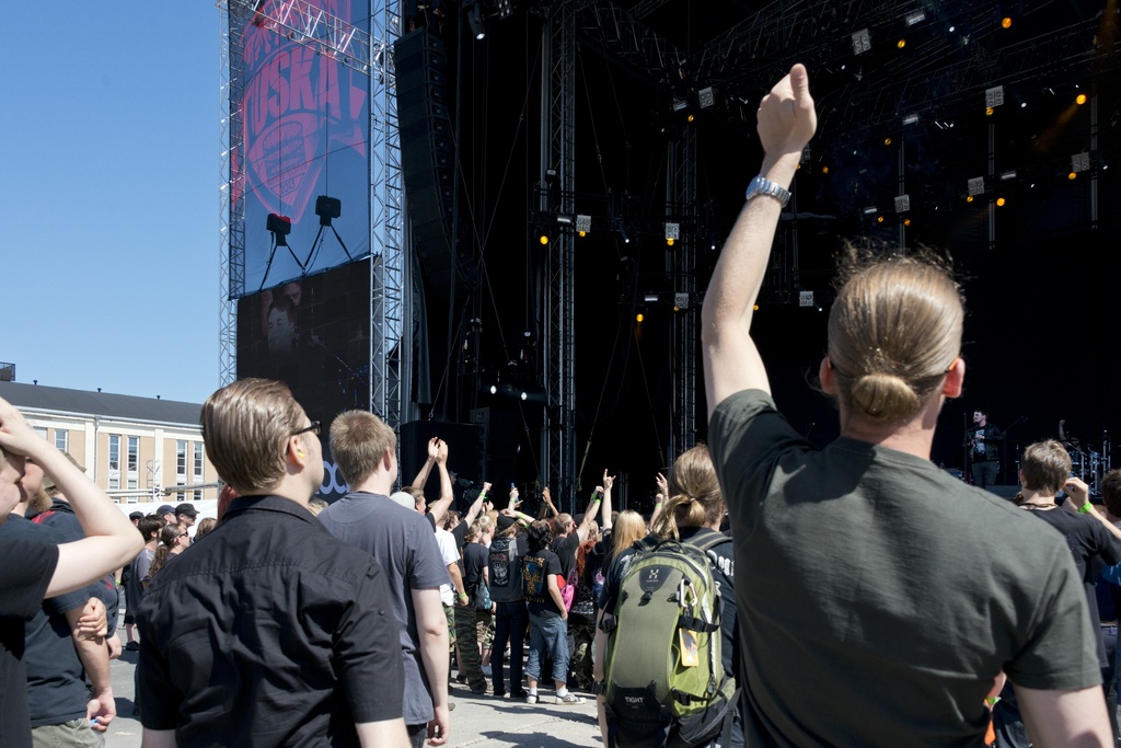 Metallimusiikkifani. Tuska-festivaalin päälavan yleisöä. Päälavalla esiintyy Tesseract -yhtye. Lavan molemmilla puolilla on isot näyttöruudut, joista musiikkiesityksiä voi seurata kauempaakin.