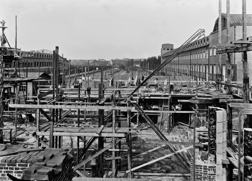 Helsingin rautatieaseman, arkkitehti Eliel Saarinen 1914, rakennustöitä. Oikealla vuonna 1909 valmistunut rautatiehallituksen hallintosiipi, joka toimi aseman valmistumiseen asti väliaikaisena asemarakennuksena. Vasemmalla on rakenteilla oleva pikatavarasiipi.