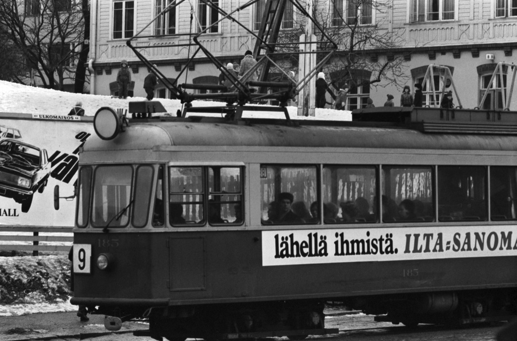 Porthaninkatu 2. 9:n raitiovaunu pysäkillä Porthaninkadulla. Raitiovaunun kyljessä mainosteksti: lähellä ihmistä. ILTA-SANOMAT. Taustalla Tukholman päiväkodin sittemmin purettu puutalo.