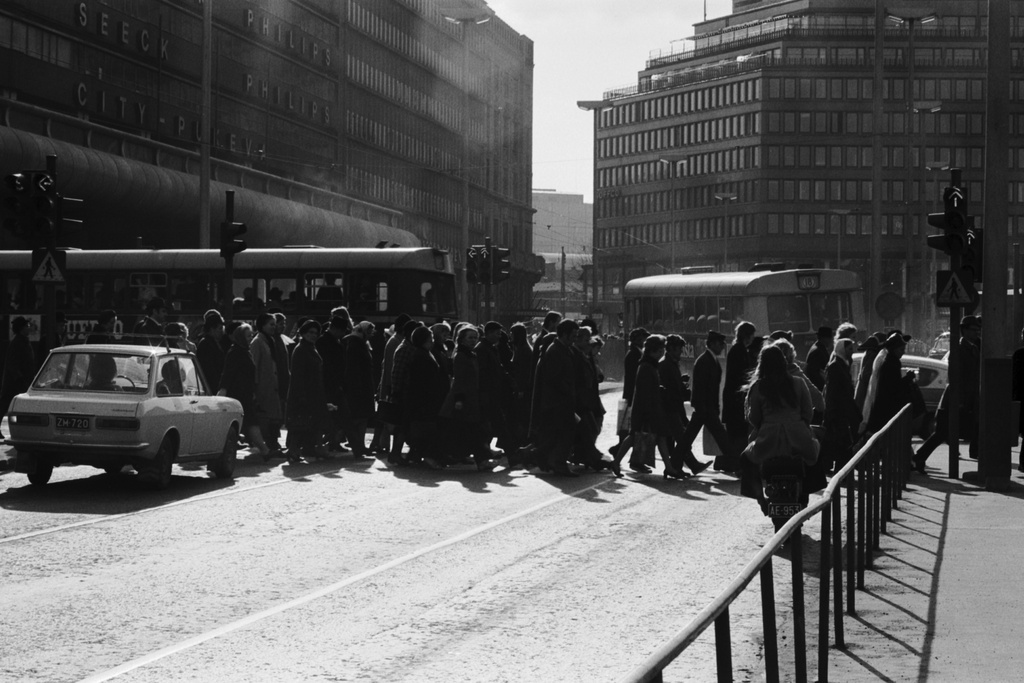 Jalankulkijoita ylittämässä iltapäivän ruuhka-aikana Kaivokatua Keskuskadun risteyksessä Makkaratalon kulmalla. Taustalla Sokoksen tavaratalo.