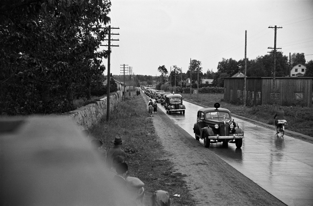 Hautasaatto saapumassa Pohjoiselle hautausmaalle (=Malmin hautausmaa). Etummainen auto Buick vm. 1937, sen takana Ford vm. 1937.