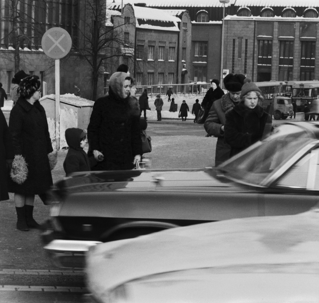 Mannerheimintie. Jalankulkijoita talvivaatteissaan odottamassa kadunylitystä Mannerheimintiellä Postikadun kulmassa. Näkymä Asema-aukion suuntaan.