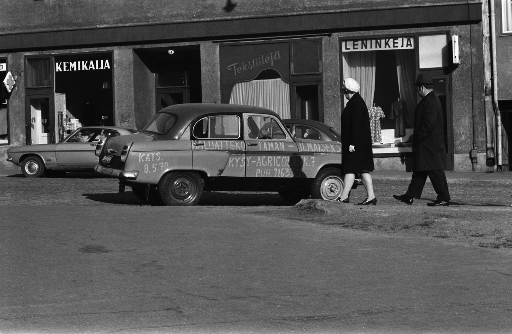 Porthaninkatu 17. Porthaninkadun ja Agricolankadun kulmassa mies ja nainen katselemassa autoa, merkkiä Moskvitsh, jonka kyljessä teksti: Haluatteko tämän ilmaiseksi? Kysy Agricolankatu 7. Puh 716335.