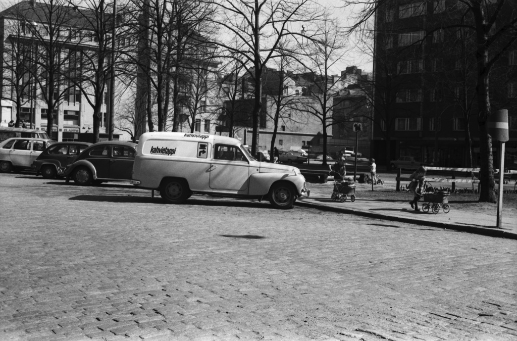 Paasivuorenkatu. Näkymä Paasivuorenkatu 5:n suunnalta kaakkoon. Etualalla Paasivuoren puistikon laidalla parkkeerattuja autoja, oikealta vasemmalle lukien: Viesti: Autot oikealta: Volvo -pakettiauto, Volkswagen, Fiat 600, Renault 16.Oikeassa reunassa kaksi nukenvaunuja työntävää tyttöä. Taustalla vasemmalla Elannon tavaratalo.