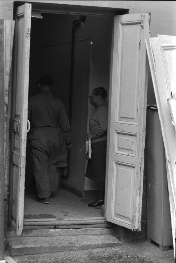 C-portaan asukas katselee kotiovellaan ohimenevän työmiehen perään Liisankatu 7:n talon saneerausremontin aikaan.