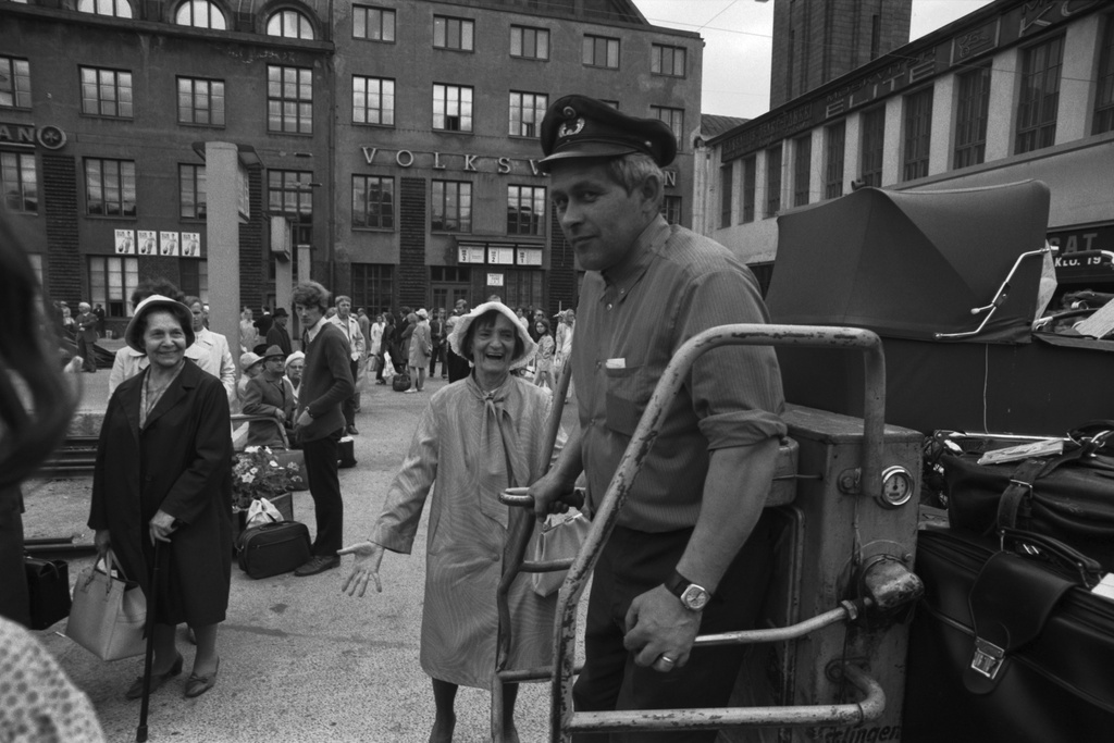Helsingin rautatieasema. Matkatavaravaunun kuljettaja ja ihmisiä asemalaiturilla Helsingin rautatieasemalla.