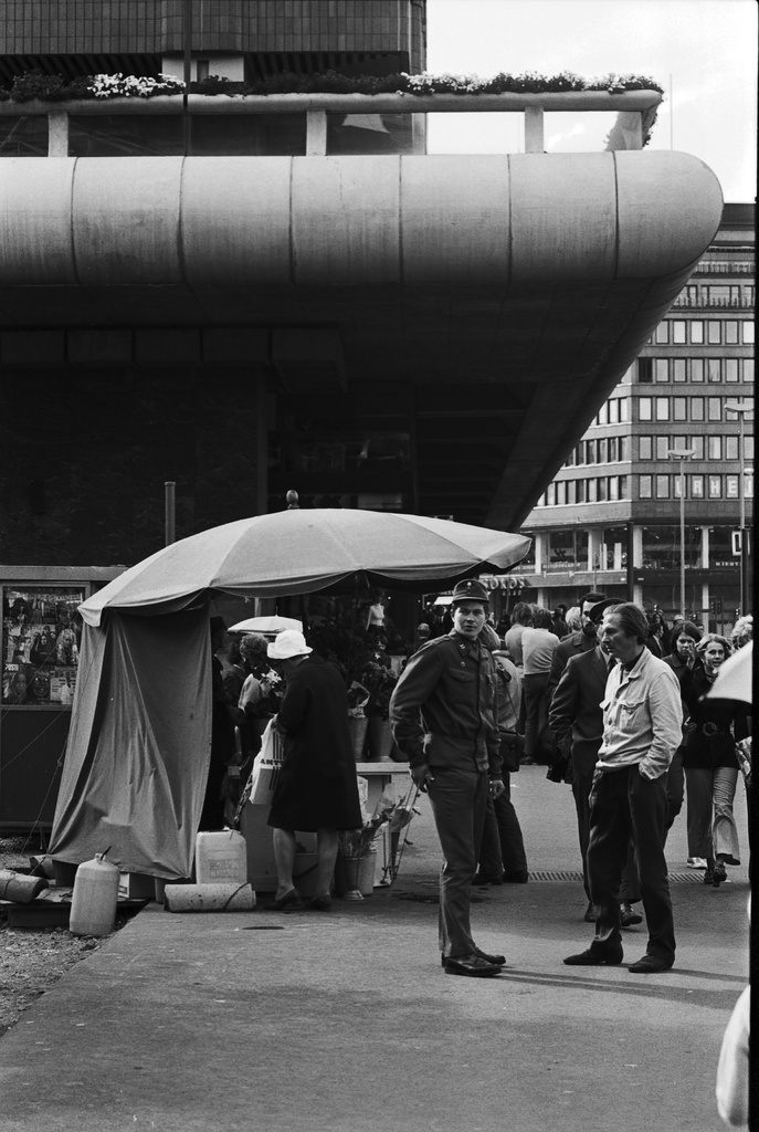 Kaivokatu. Keskuskatu 8. Ihmisiä ja kukkakioski Makkaratalon kupeessa Kaivokadulla Keskuskadun kulmassa.