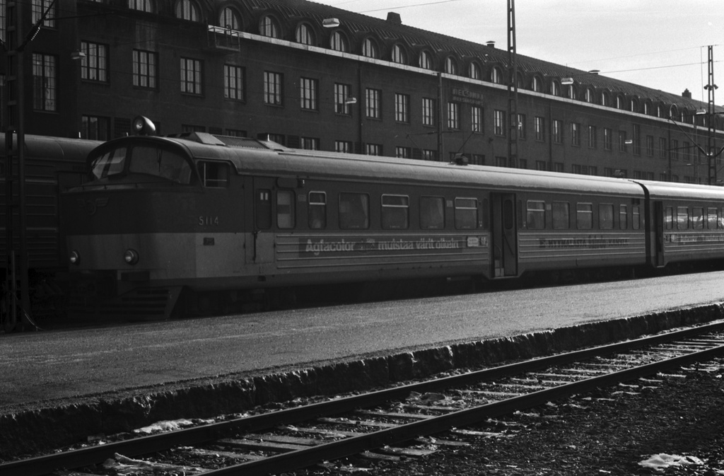 Helsingin rautatieasema. Junia Helsingin rautatieasemalla. Etualalla Dm9-sarjan moottorijunan kyljessä mainos: Agfacolor muistaa värit oikein.