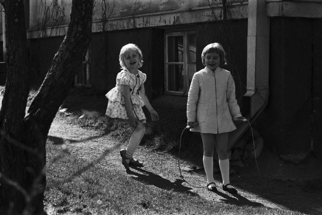 Torkkelinmäki. Kaksi  iloista tyttöä hyppimässä narua pihalla Torkkelinkatu 5:n edustalla  Torkkelinaukion kulmassa.