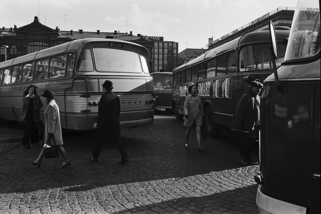 Ihmisiä puikkelehtimassa bussien välissä iltapäivän ruuhka-aikaan Rautatientorilla.