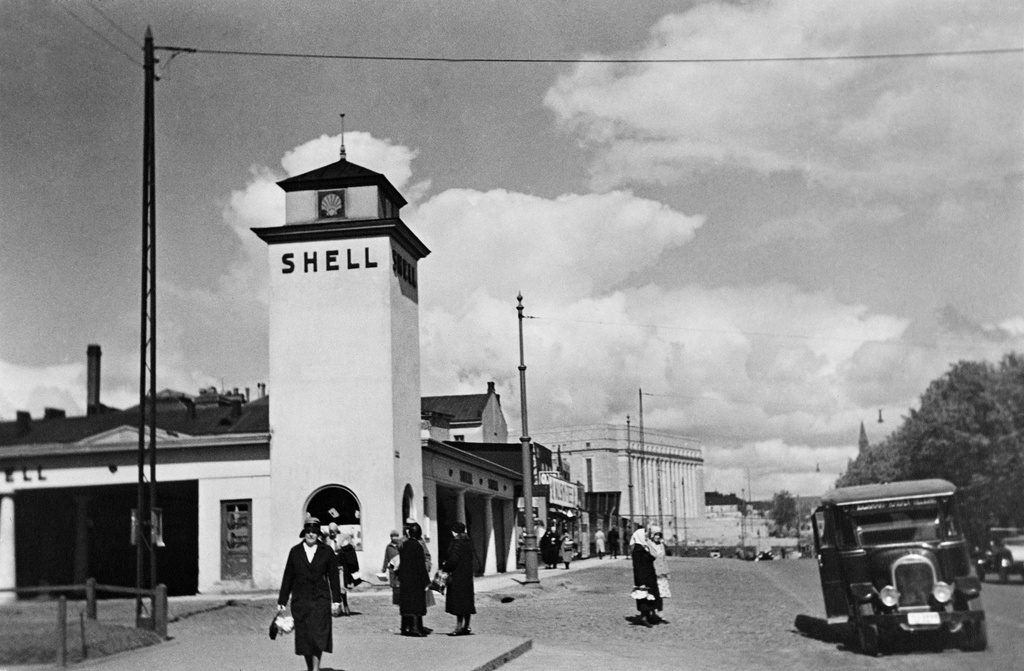 Oy Shell Ab:n huoltoasema Läntisellä Heikinkadulla. Simonkatu 1-Heikinkatu 28 (= Mannerheimintie 22-24). Eduskuntatalo taustalla. Huoltamo rakennettu 1928, purettu 1934.