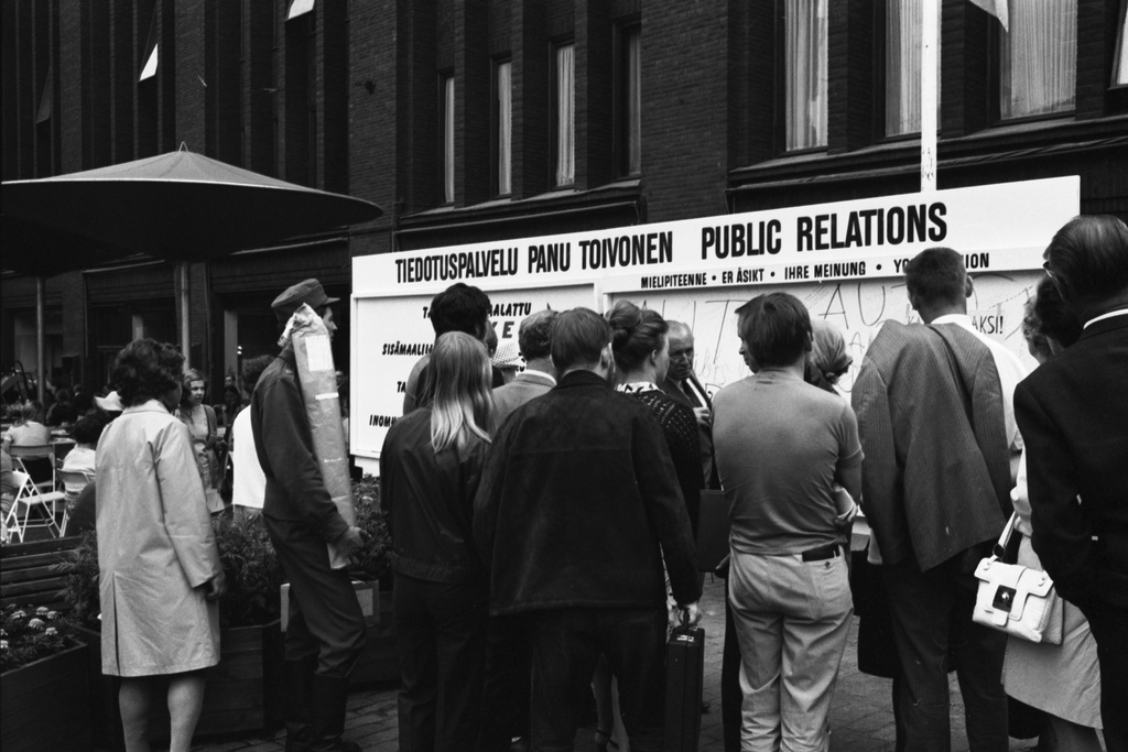 Aleksanterinkatu 52. Ihmisiä Tiedotuspalvelu Panu Toivosen mainos- ja mielipidetaulun äärellä Stockmannin tavaratalon edustalla kävelykatukokeilun avajaispäivänä.