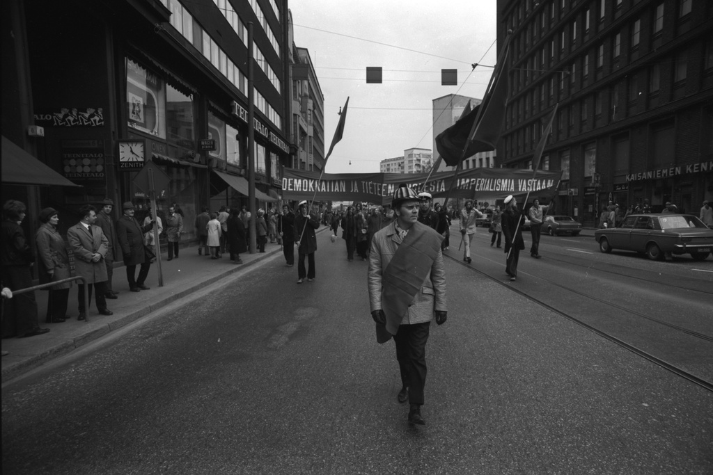 Kaisaniemenkatu 6. Työväen vappukulkue Kaisaniemenkadulla lippuineen ja julisteineen 1.5.1972. Kärjessä airut, taustalla julisteessa teksti: Demokratian ja tieteen puolesta imperialismia vastaan.