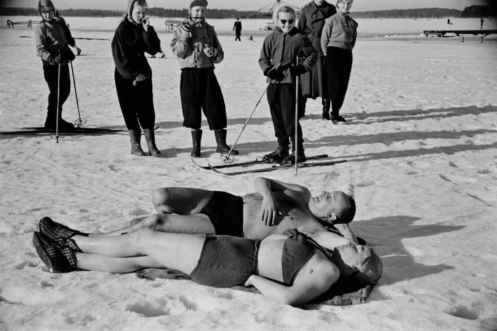 Avantouintia Taivallahdella. Uimarit ottavat aurinkoa uinnin jälkeen, nainen virkatuissa bikineissä. Ympärillä yleisöä.