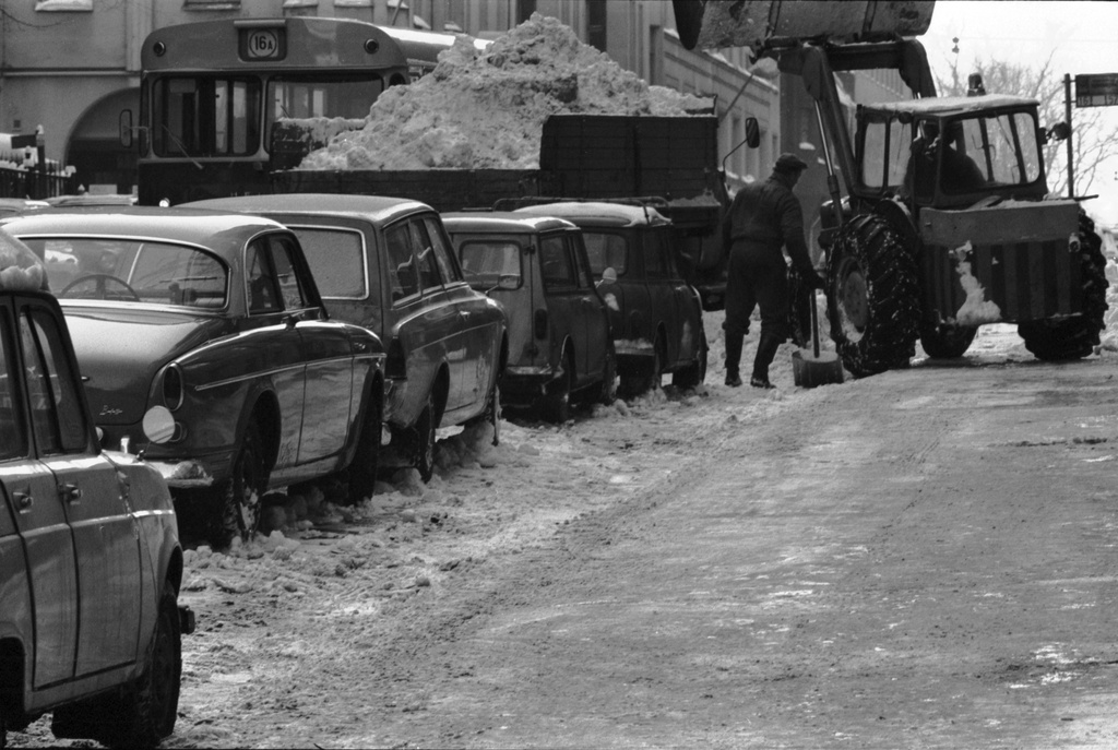 Liisankatu. Traktori lastaamassa lunta kuorma-auton lavalle Liisankadulla. Vasemmalla bussi 16 A Mariankadun kulmassa. Pysäköidyt ajoneuvot tunnistettu seuraavasti (vasemmalta oikealle): Renault 4, Volvo Amazon, Ford 17M Turnier, Austin/Morris Mini -pakettiauto, Austin/Morris Mini.