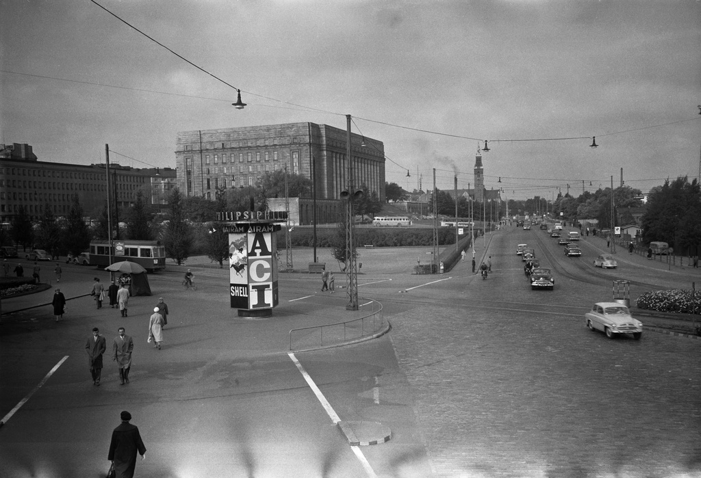 Liikennettä Mannerheimintien ja Arkadiankadun risteyksessä, taustalla Eduskuntatalo. Keskellä Philipsin, Airamin ja Shellin pyörivä ulkomainos.