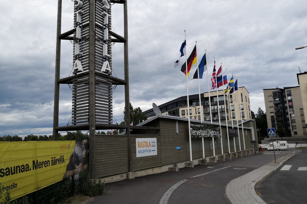 Kesäinen Rastilan leirintäalue. Etualalla vastaanottorakennus, jonka edessä liehuu eri maiden lippuja. rephoto