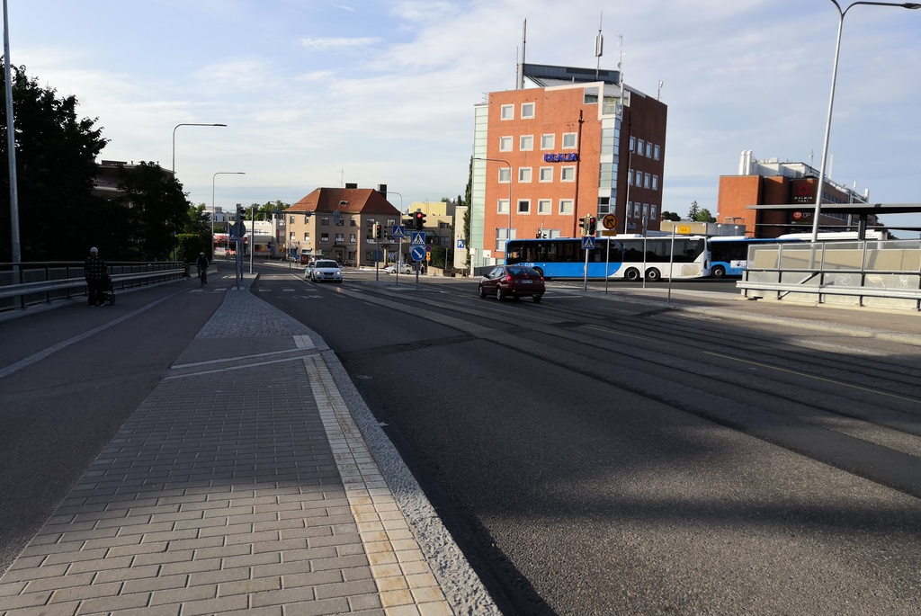 Malmi, Ylä-Malmi, Kirkonkyläntie. Näkymä pääradan ylittävältä maantiesillalta Kirkonkyläntien alkupäästä pohjoiseen, Ylä-Malmin suuntaan. Vasemmalla Malmin Elannon rakennuksessa  E-Alennushalli. Oikealla Suomen Maanviljelijäin Kauppa SMK:n myyntikonttori ja varasto paikalla, jossa nykyisin on Malmin kauppakeskus ja Ylä-Malmin tori. rephoto