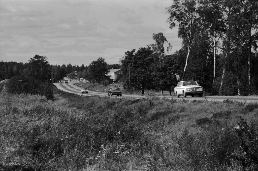 Viikintie. Viikintietä länteen. Taustalla tienviitat vasemmalle Keskustaan, oikealle Lahteen ja Malmille. Vasemmalla Viikin Unionin huoltoasema. Puiden katveessa puurakenteinen kartanorakennus, nykyinen Viikinkaari 8.