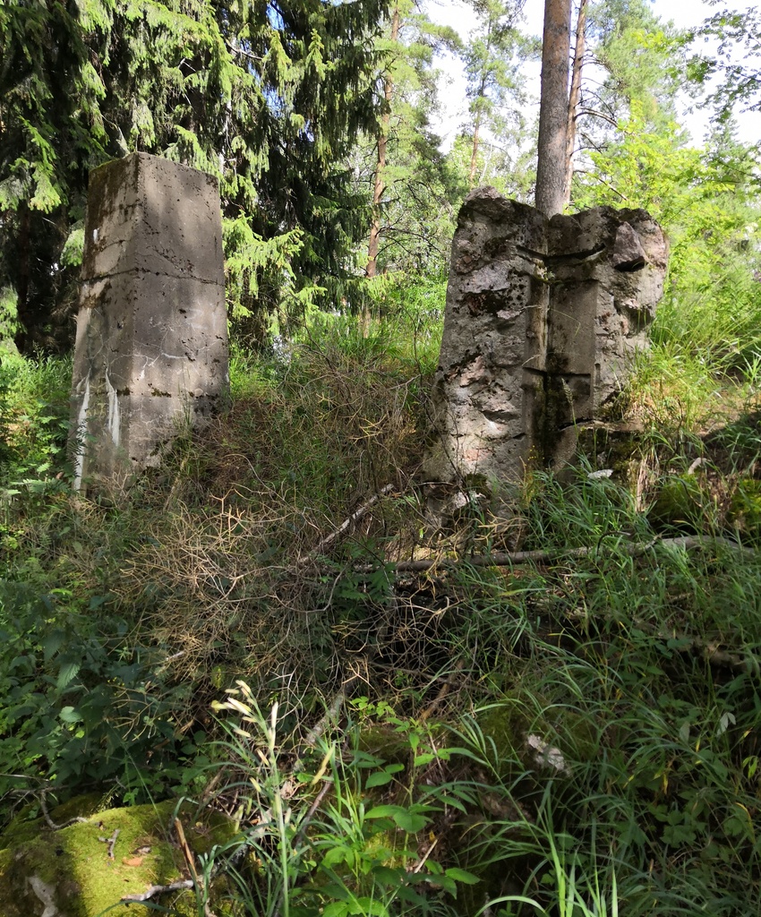 Myllypuro. Ensimmäisen maailmansodan aikainen maalinnoitus, tykkipatteri 65 Myllypurossa. Kuvassa näkyy kaksi pohjoisimman suojahuoneen viidestä betonisesta savupiipusta tai hormista. Vasemmanpuolimmainen hormi on ehyt ja sen kylkeen on maalattu ihmishahmoa esittävä vihertävä graffiti. Oikeanpuolimainen hormi on pahasti vaurioitunut, vain yksi hormin kulmista on enää pystyssä. Kulmissa näkyy painanteina hormia tukeneista vahvikkeista. Kuvaussuuntana pohjoinen. rephoto