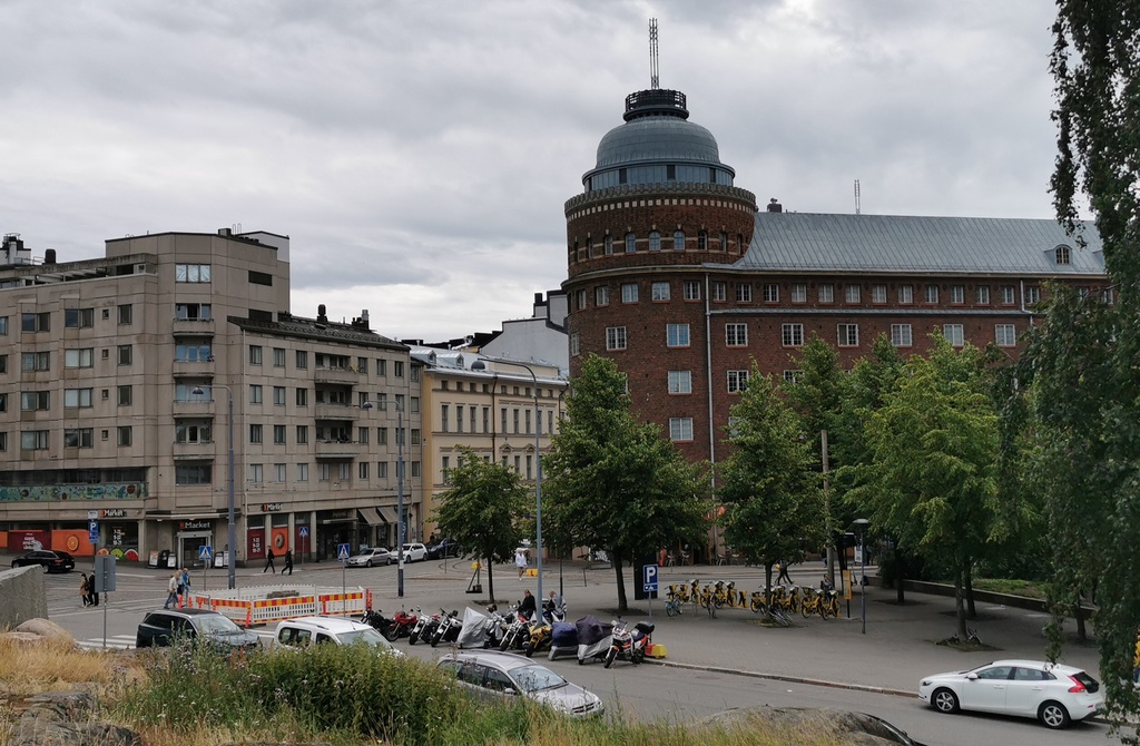 Rakennuksia ja aidattu puutavaran varastointialue nykyisen Ympyrätalon paikalla. Oikealla Porthaninrinne 1 ja 3. Vasemmalla Toinen linja 5 ja Porthaninkatu 1. Taustalla Arena talo. rephoto