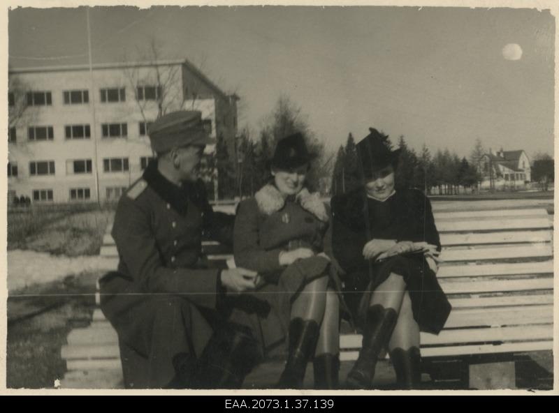 A German-style soldier on the bench simultaneously with two women