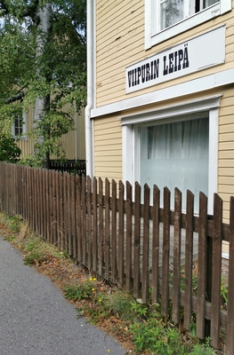 Viipurin Leipä Oy:n leipomon myymälä puurakennuksessa Toukolassa. Myymälän näyteikkuna ja sisäänkäynti. Rakennuksen ulkoseinässä on viipurinrinkelin muotoinen mainoskyltti. rephoto