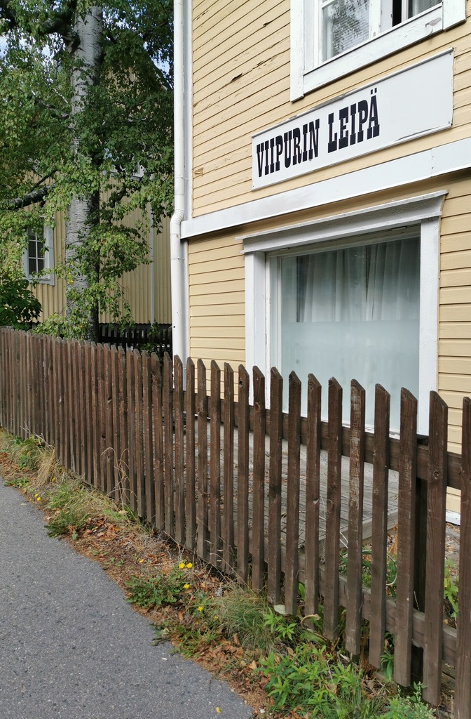 Viipurin Leipä Oy:n leipomon myymälä puurakennuksessa Toukolassa. Myymälän näyteikkuna ja sisäänkäynti. Rakennuksen ulkoseinässä on viipurinrinkelin muotoinen mainoskyltti. rephoto