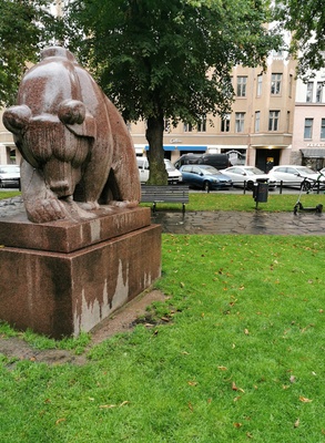 Nainen ja sotilasunivormuinen mies Karhupuistossa, vasemmalla kuvanveistäjä Jussi Mäntysen veistos Mesikämmen muurahaispesällä. Taustalla kerrostalo Agricolankatu 13. rephoto