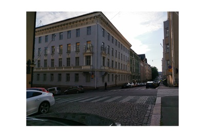Pysäköityjä autoja ja lunta kadun varressa Rauhankadulla. Näkymä Meritullinkadun kulmasta länteen, Mariankadun suuntaan. Edessa tien toisella puolella näkyy Rauhankatu 4 ja Meritullinkatu 10 kulmaan asettuva patsain koristeltu rakennus. Rakennus on Georg Wasastjernan suunnittelema, 1914 rakennettu ja tyyliltään klassistinen. Talo on ollut opetusministeriön käytössä vuodesta 1968. rephoto
