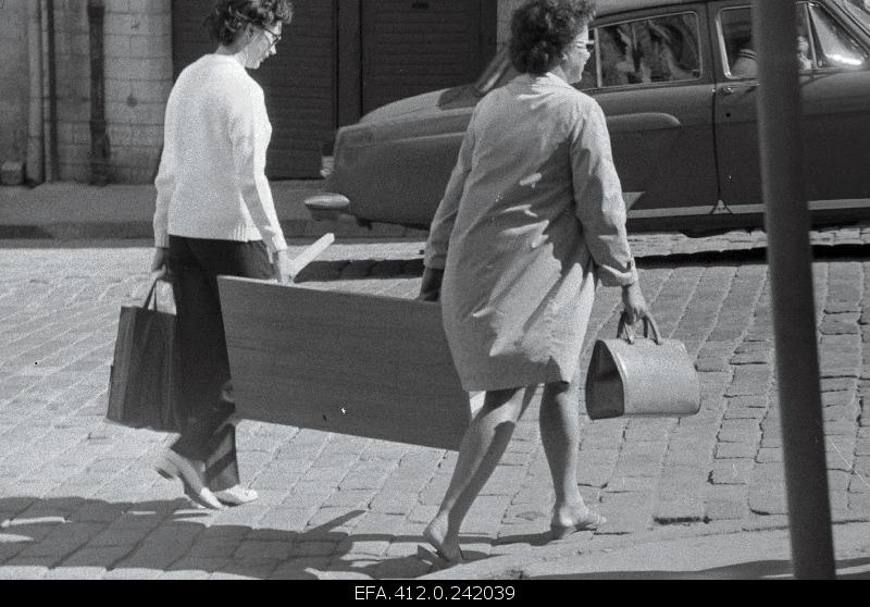 Two women on the street wearing a sofa table.