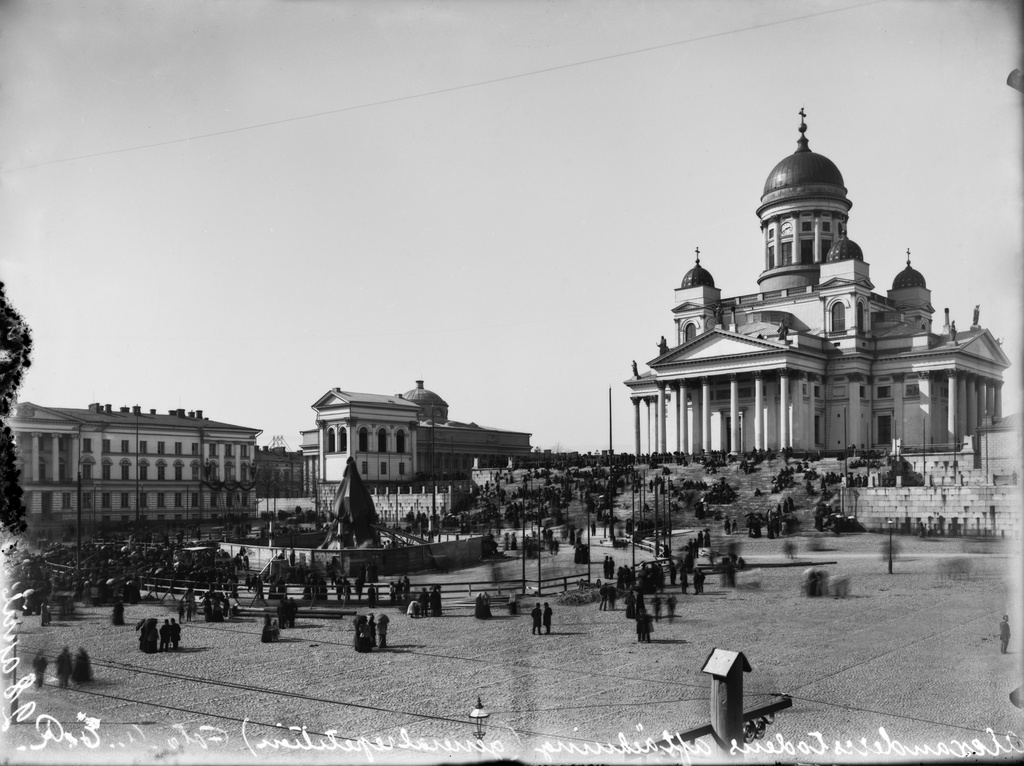 Aleksanteri II:n muistopatsaan paljastustilaisuuden järjestelyjä Senaatintorilla päivää ennen paljastusta. Taustalla Nikolainkirkko (=Suurkirkko, Helsingin tuomiokirkko), vasemmalla Keisarillisen Aleksanterin-Yliopiston (=Helsingin yliopisto) päärakennus.