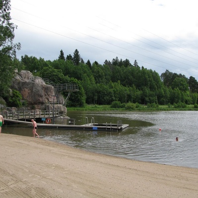 Pikkukosken uimaranta Vantaanjoen rannalla. Uimareita vedessä ja rannalla. Taustalla vesiliukumäki. Veräjämäki. rephoto