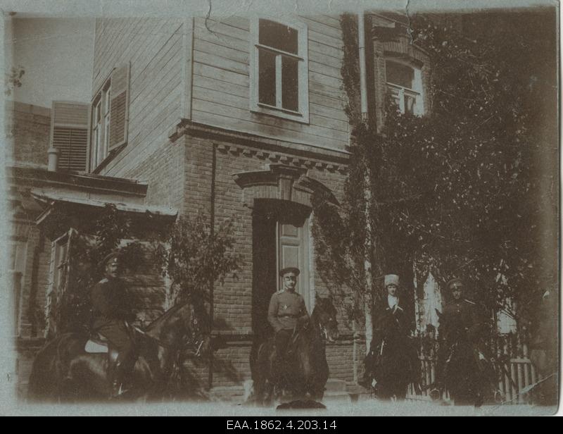 Four soldiers standing on horses at the entrance to the house