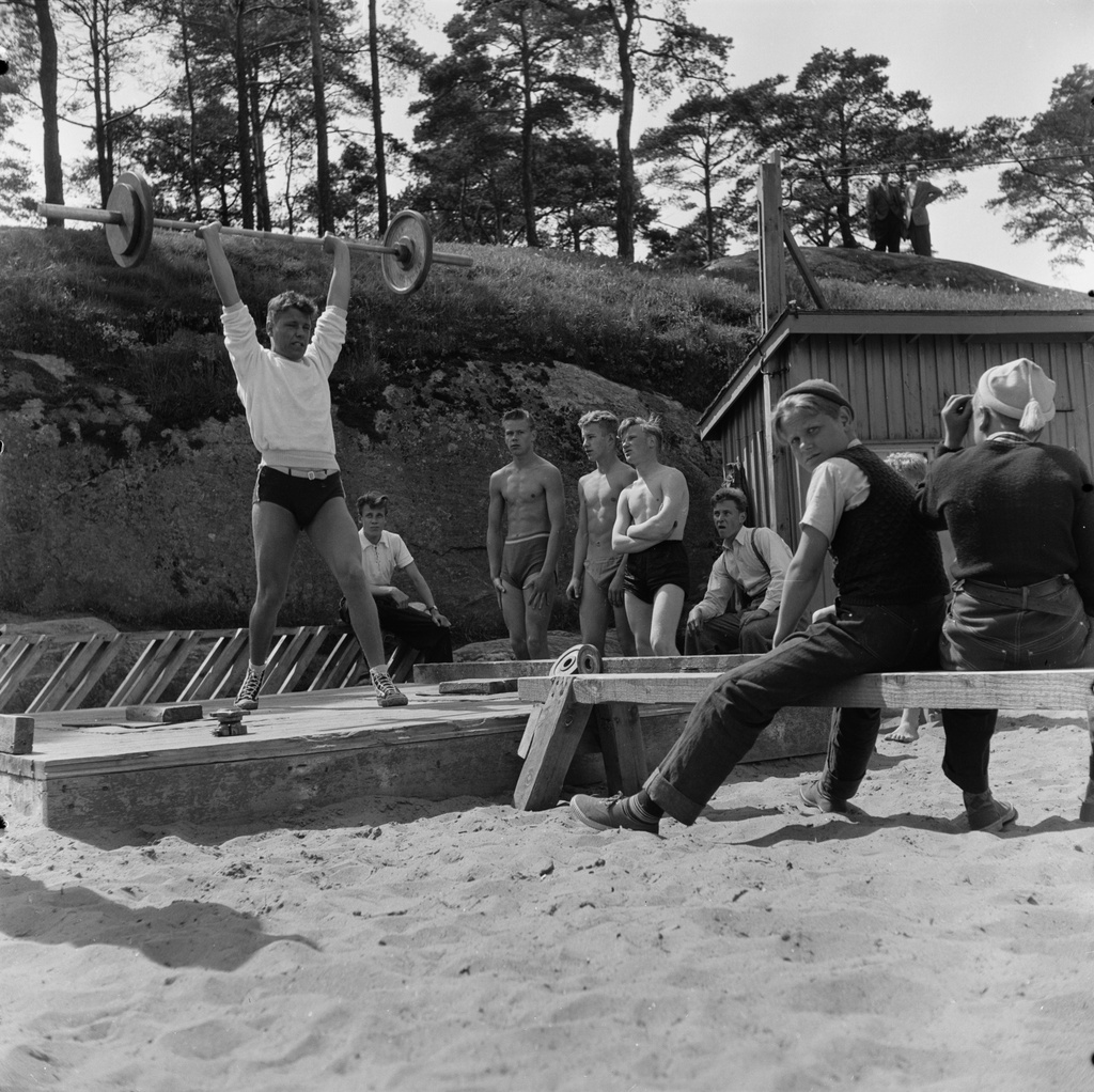 Miehet nostavat painoja Hietaniemen uimarannalla.