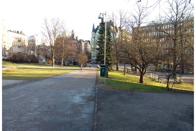 Katajanokka. Näkymä Kanavakadulta itään Satamakadun suuntaan, nykyisin paikalla on Tove Janssonin puiston puistokäytävä. Vasemmalla luminen Katajanokan puisto. Taustalla keskellä Satamakatu 5:n kerrostalo Luotsikadun ja Kruunuvuorenkadun kulmassa. rephoto